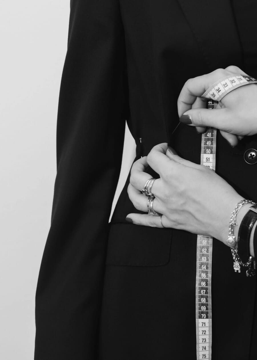 Measuring the sleeve of a black jacket with a tape measure