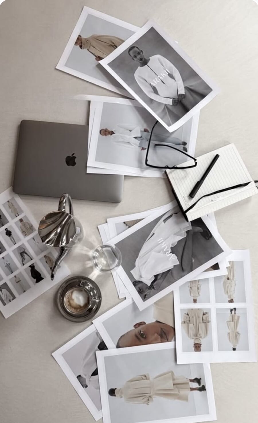 Printed reference photos spread on a table around a laptop