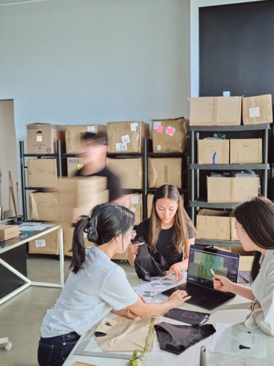Team at a table with laptops in front of shelves of sample boxes