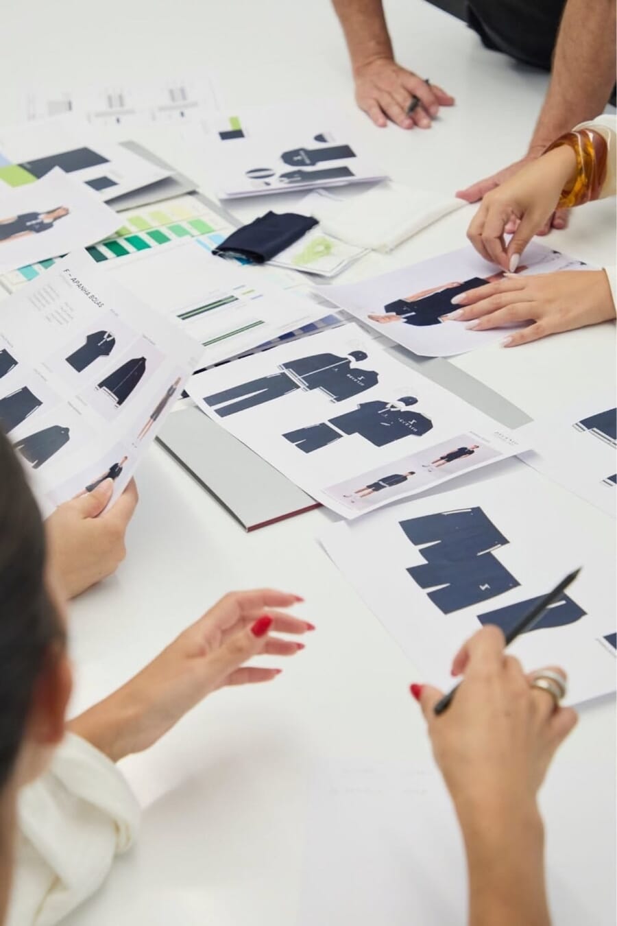 Flat sketches and color cards spread across a white table
