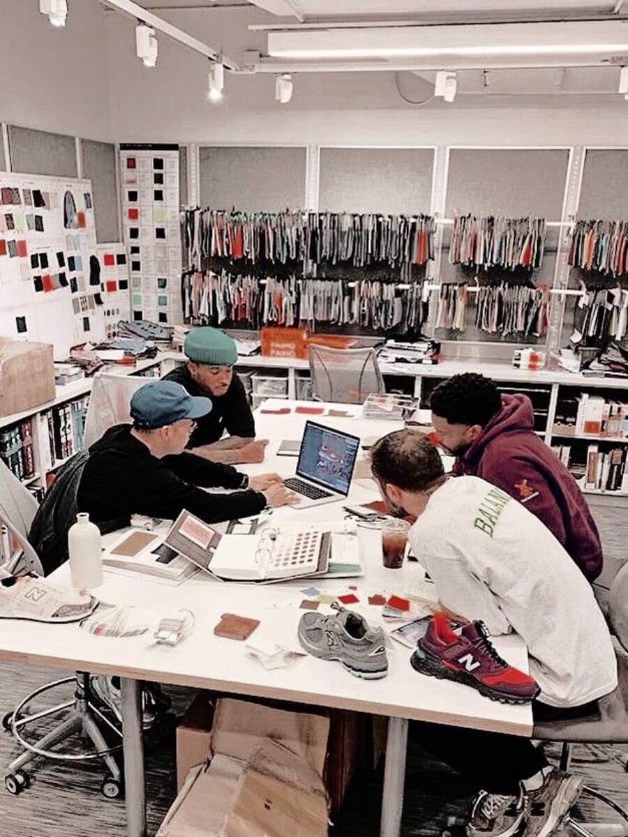 Team at a long table with laptops and sneaker samples in front of clothing rails