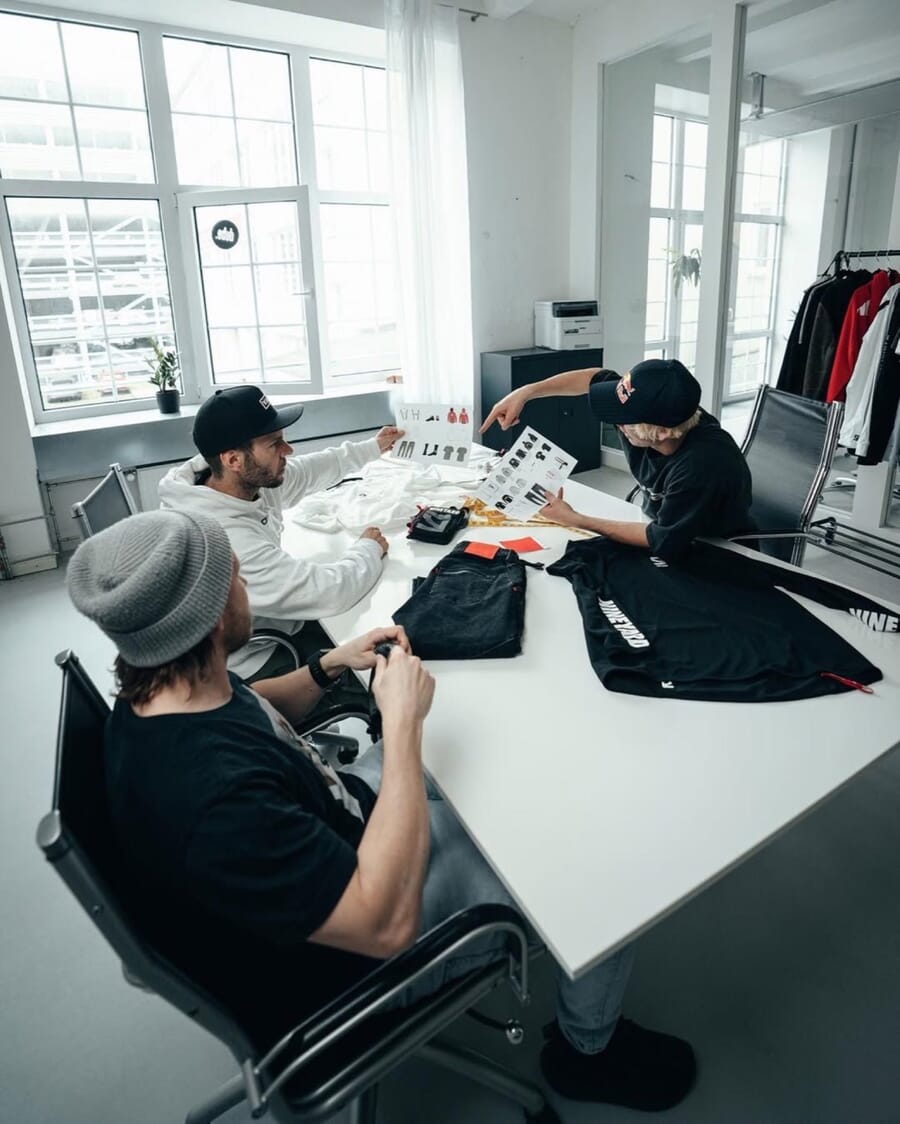 Team at a table reviewing black garment samples beside large windows