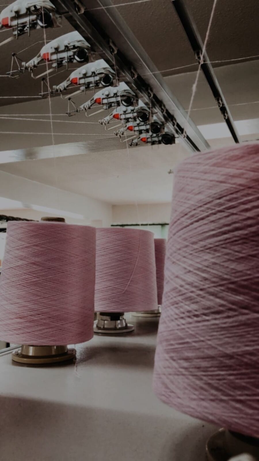 Large cones of pink yarn on a knitting room floor