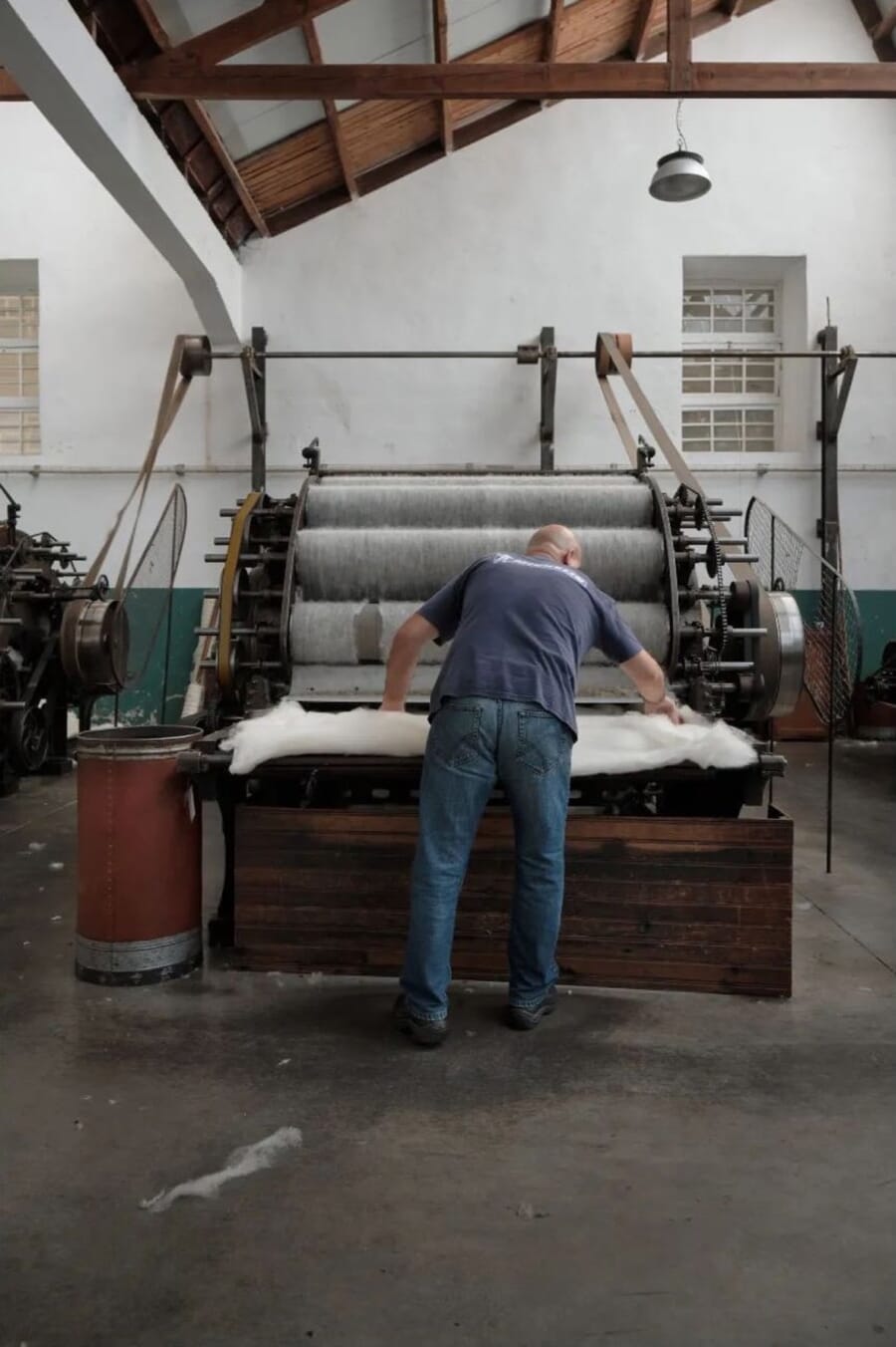 Worker feeding wool fibre into a carding machine in a mill
