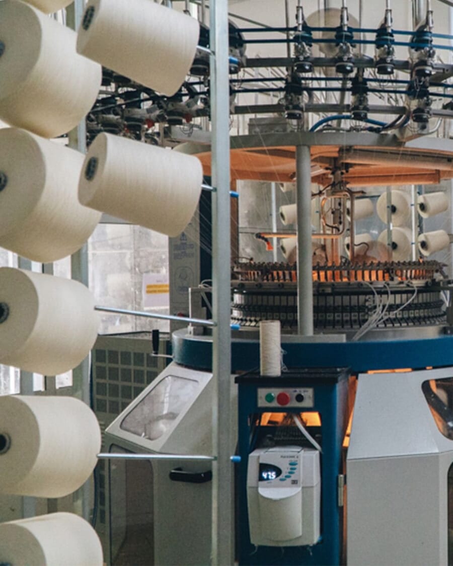 Circular knitting machine fed by white yarn cones