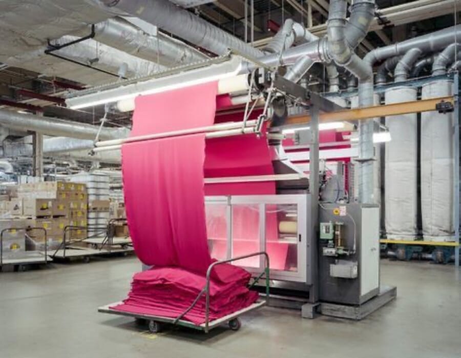Pink fabric running through a finishing machine