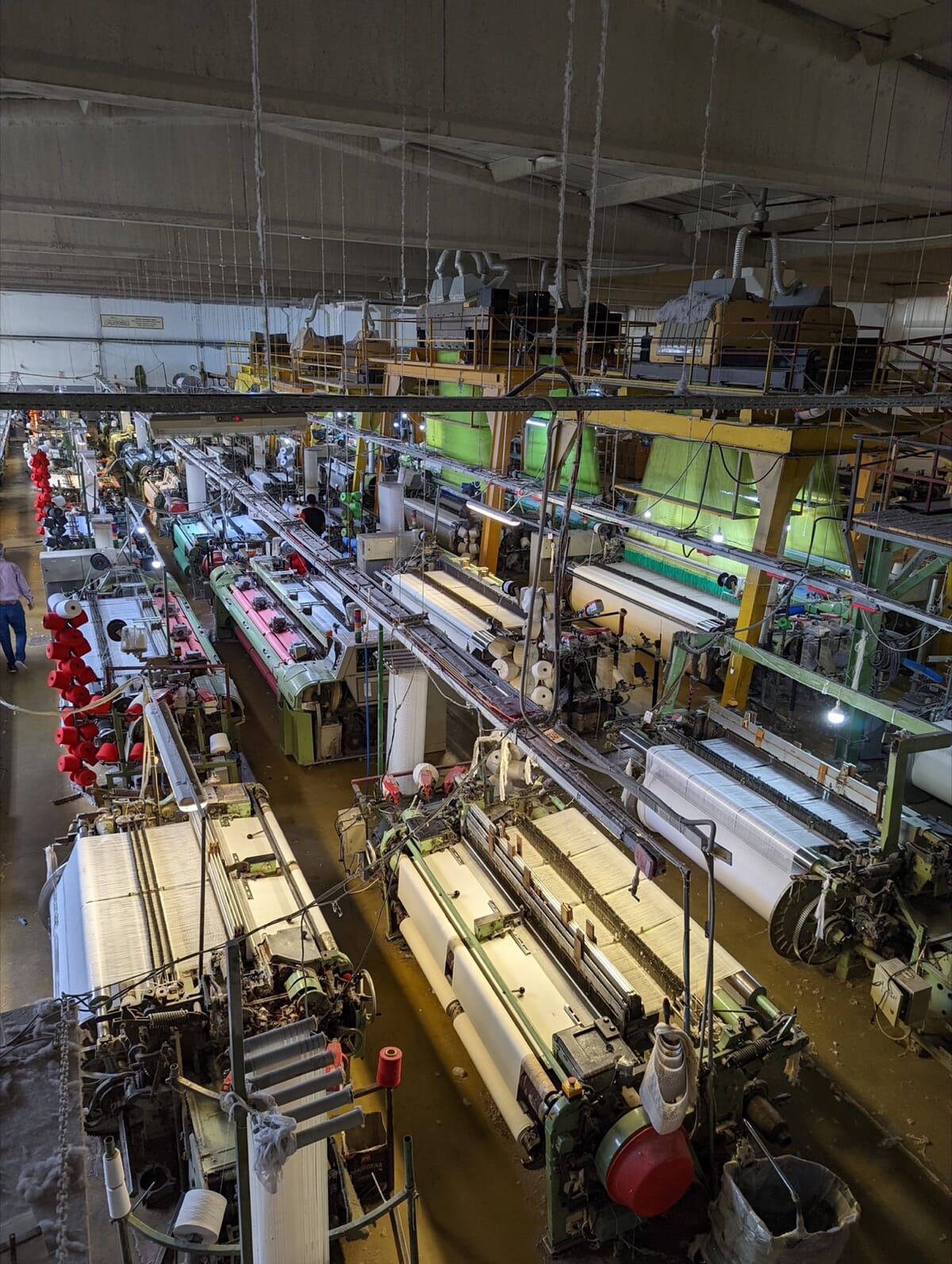 Weaving hall with rows of looms weaving white cloth