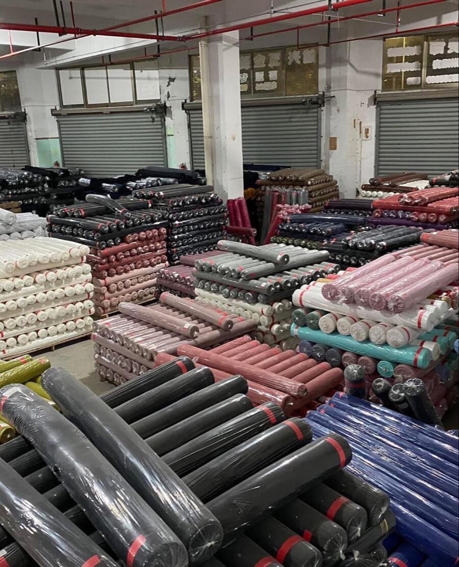Fabric store piled high with rolls of black, pink, red and blue fabric