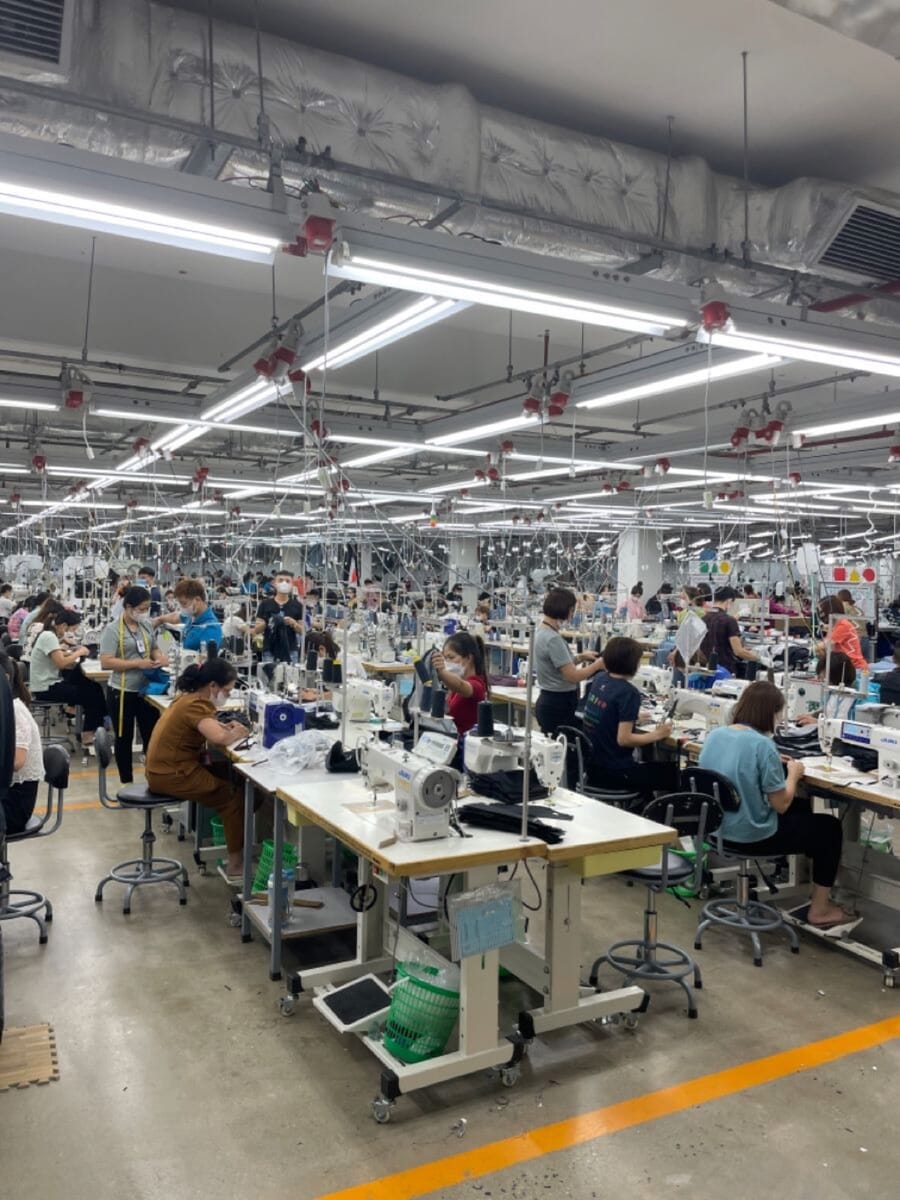 Long rows of sewing stations with operators at work under bright strip lights