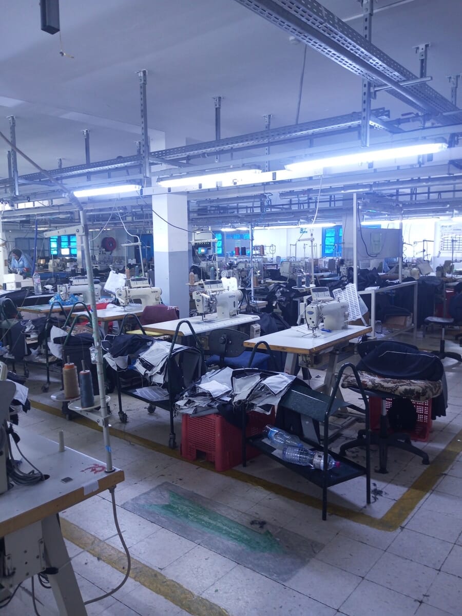 Sewing stations with dark garments draped over the tables and lights overhead