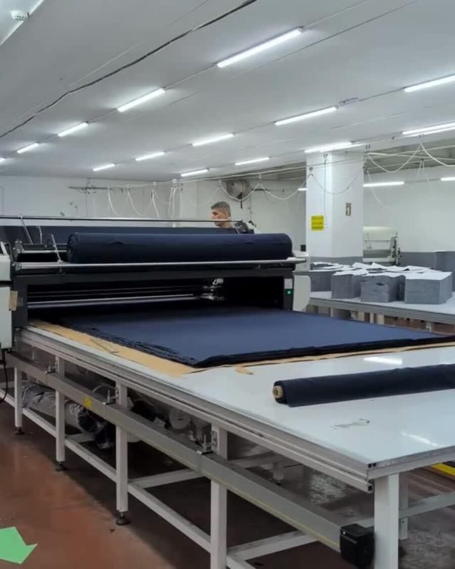 Spreading machine laying indigo fabric in layers along a long cutting table