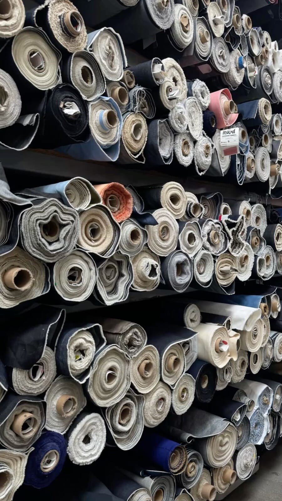 Racks of rolled denim and twill fabric seen end on