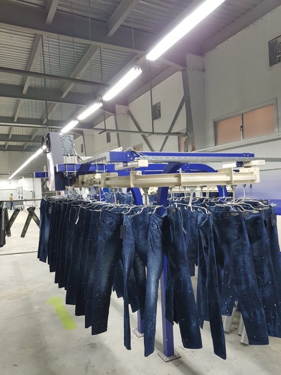 Rows of washed jeans hanging from an overhead conveyor