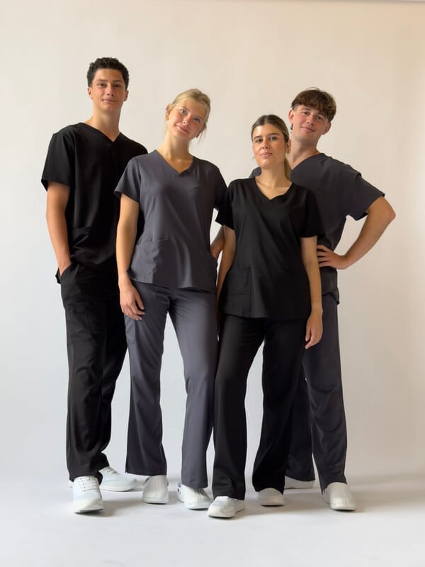 Four healthcare staff in black and charcoal scrub tops and trousers