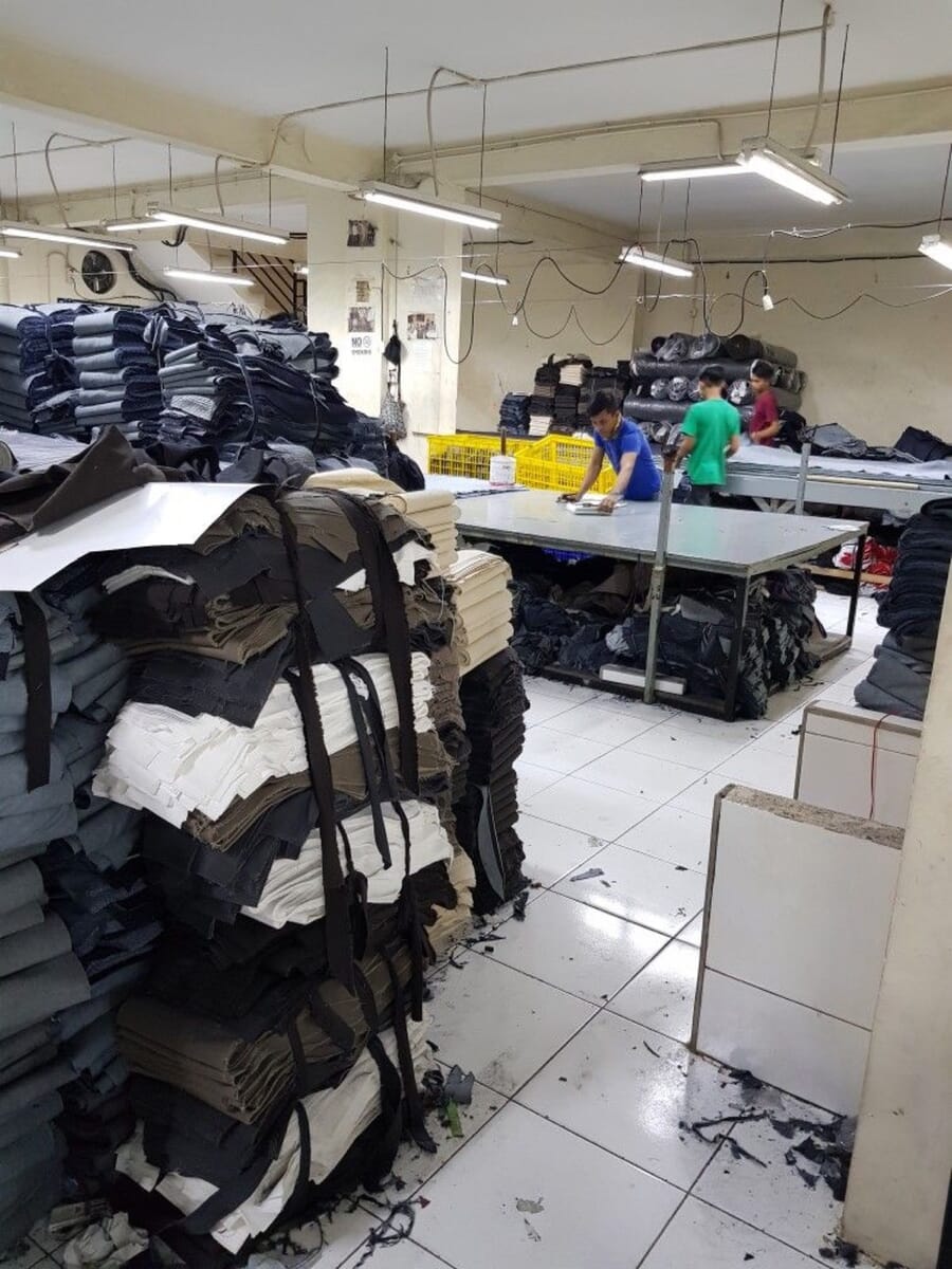 Tall stacks of cut denim bundles waiting beside the cutting tables