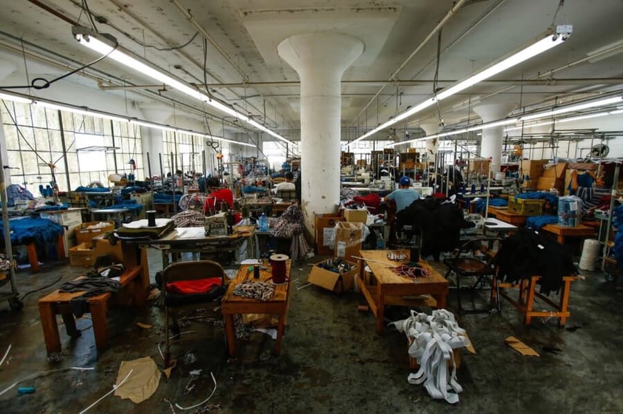 Large sewing floor with concrete columns, work tables and bins of cut pieces