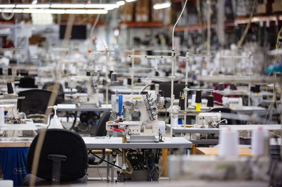 Rows of industrial sewing machines lined up across a factory floor