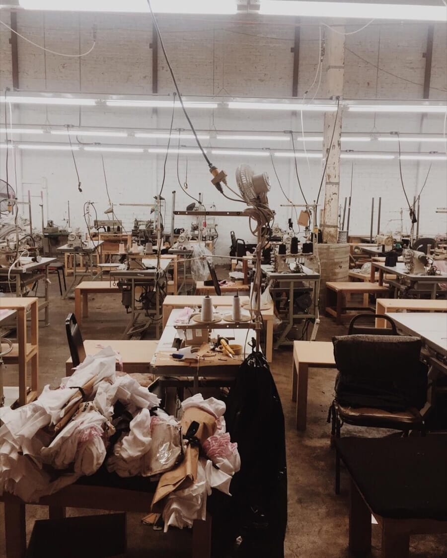 Workroom with rows of sewing tables, chairs and bundles of fabric
