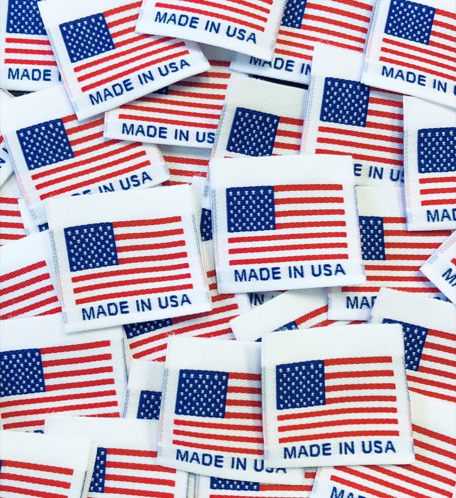 Pile of white woven labels, each with a US flag and the words Made in USA