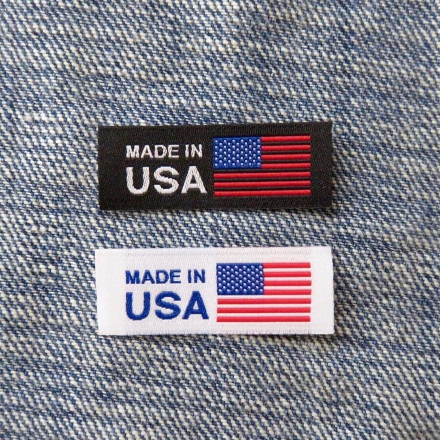 Two woven Made in USA labels with US flags laid on denim fabric
