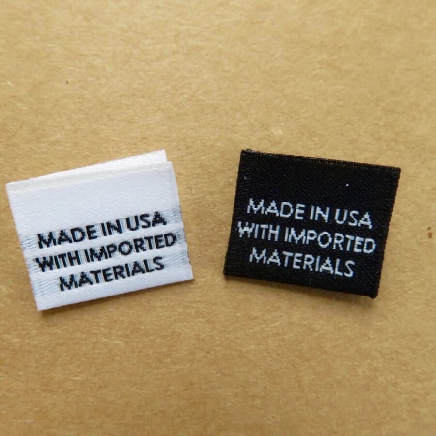 Two woven labels reading Made in USA with imported materials, one white and one black