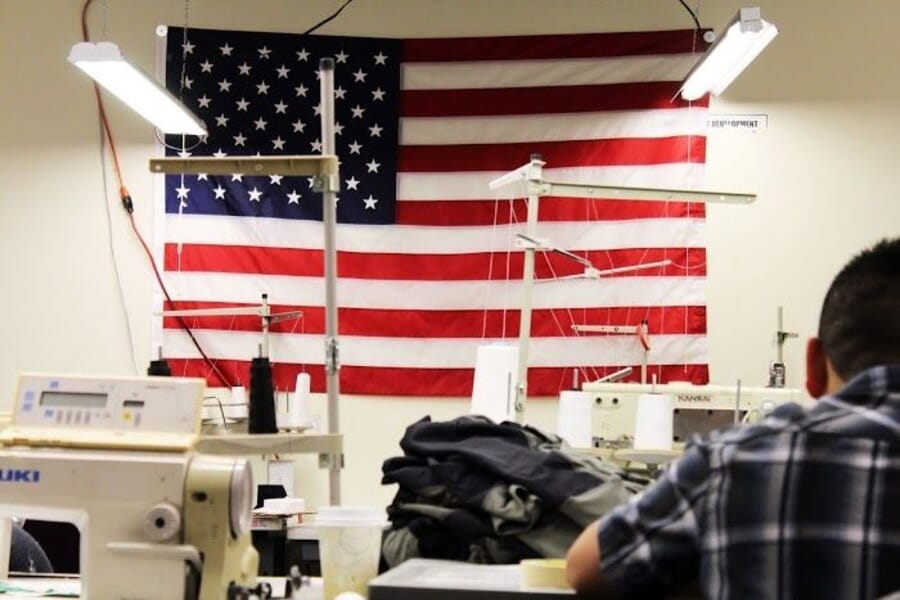 Operator at a sewing machine in front of a US flag on the wall