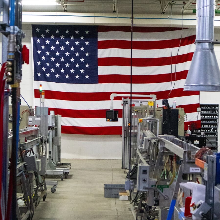 Large US flag on the wall behind a row of industrial machines