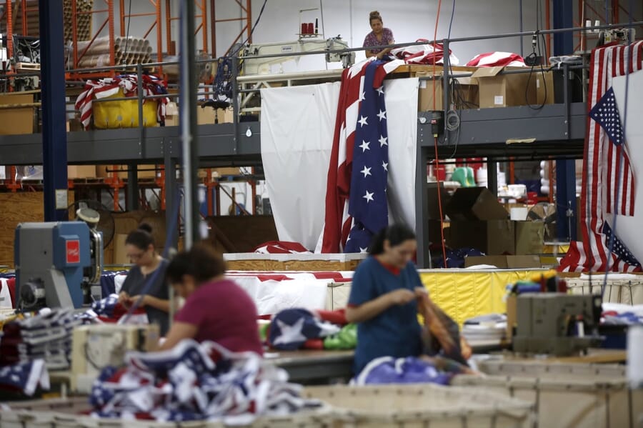 Operators sewing on a line with US flags hung around the workroom