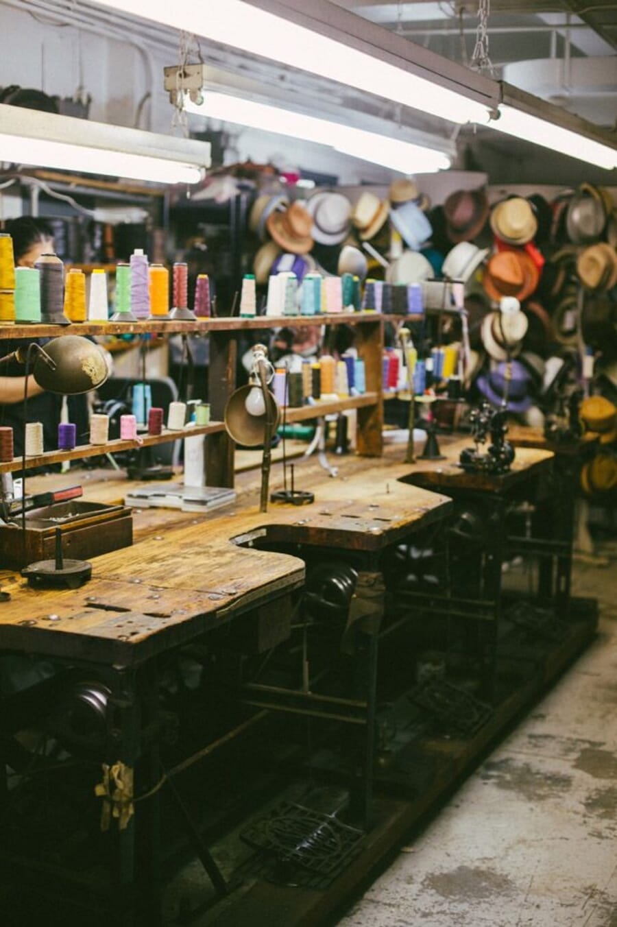Wall of colourful thread cones above wooden cutting tables