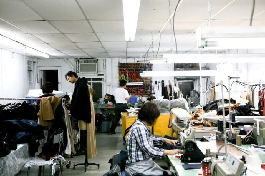 Bright sewing room with operators at machines and garments on a rail