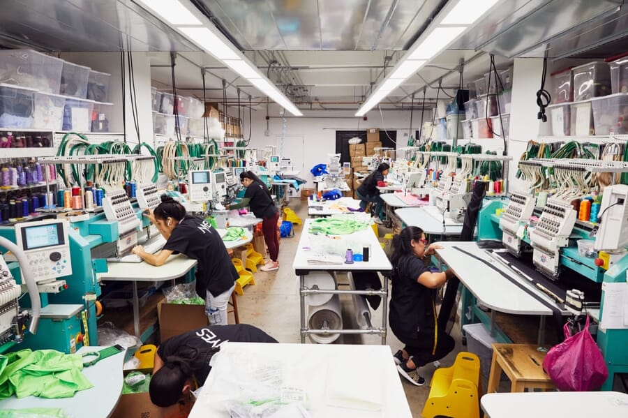 Operators working at multi-head embroidery machines with bright green garments