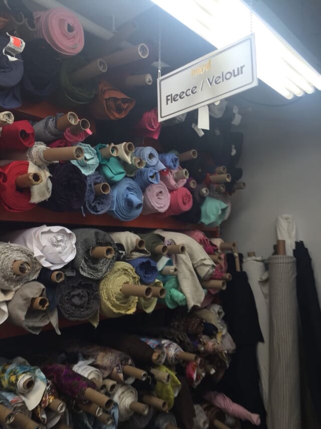 Shelves of fabric rolls sorted by colour in a fabric store