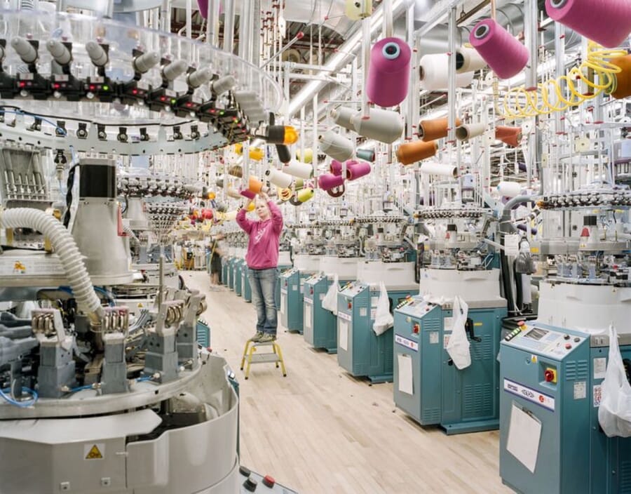 Circular knitting machines with yarn cones overhead on a knitting floor
