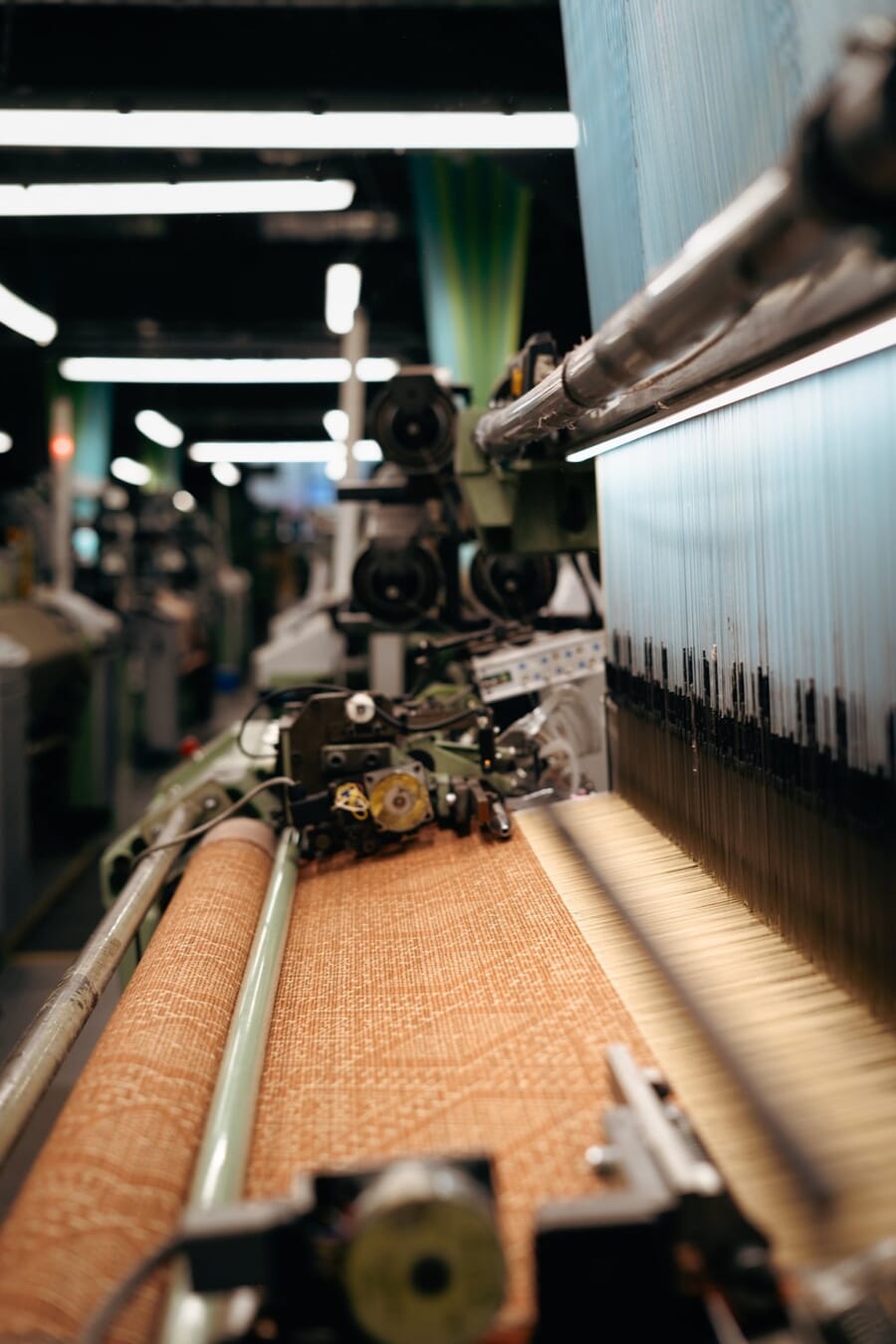 Close-up of fabric being woven on a loom in a textile mill