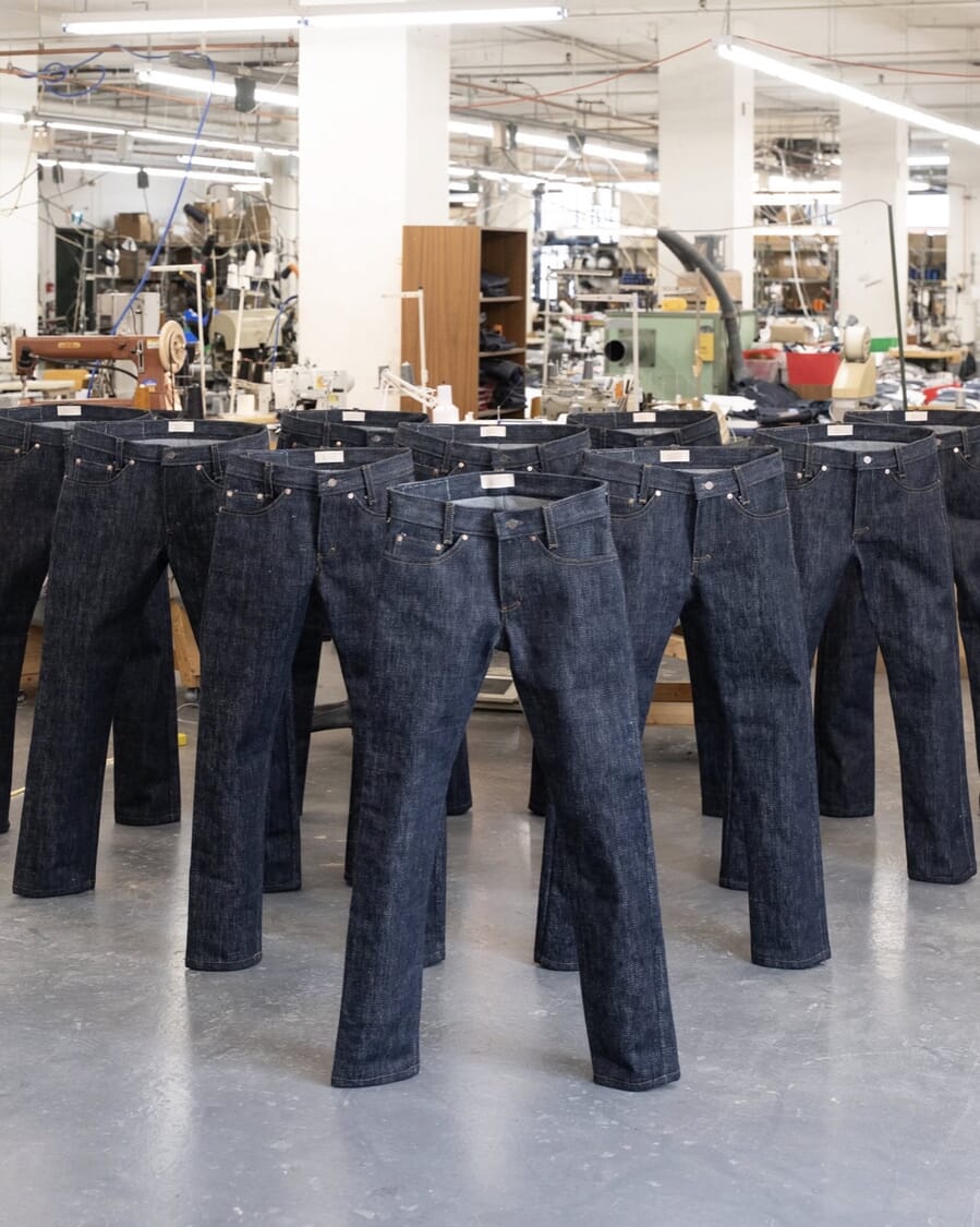 Rows of raw denim jeans standing upright on a factory floor