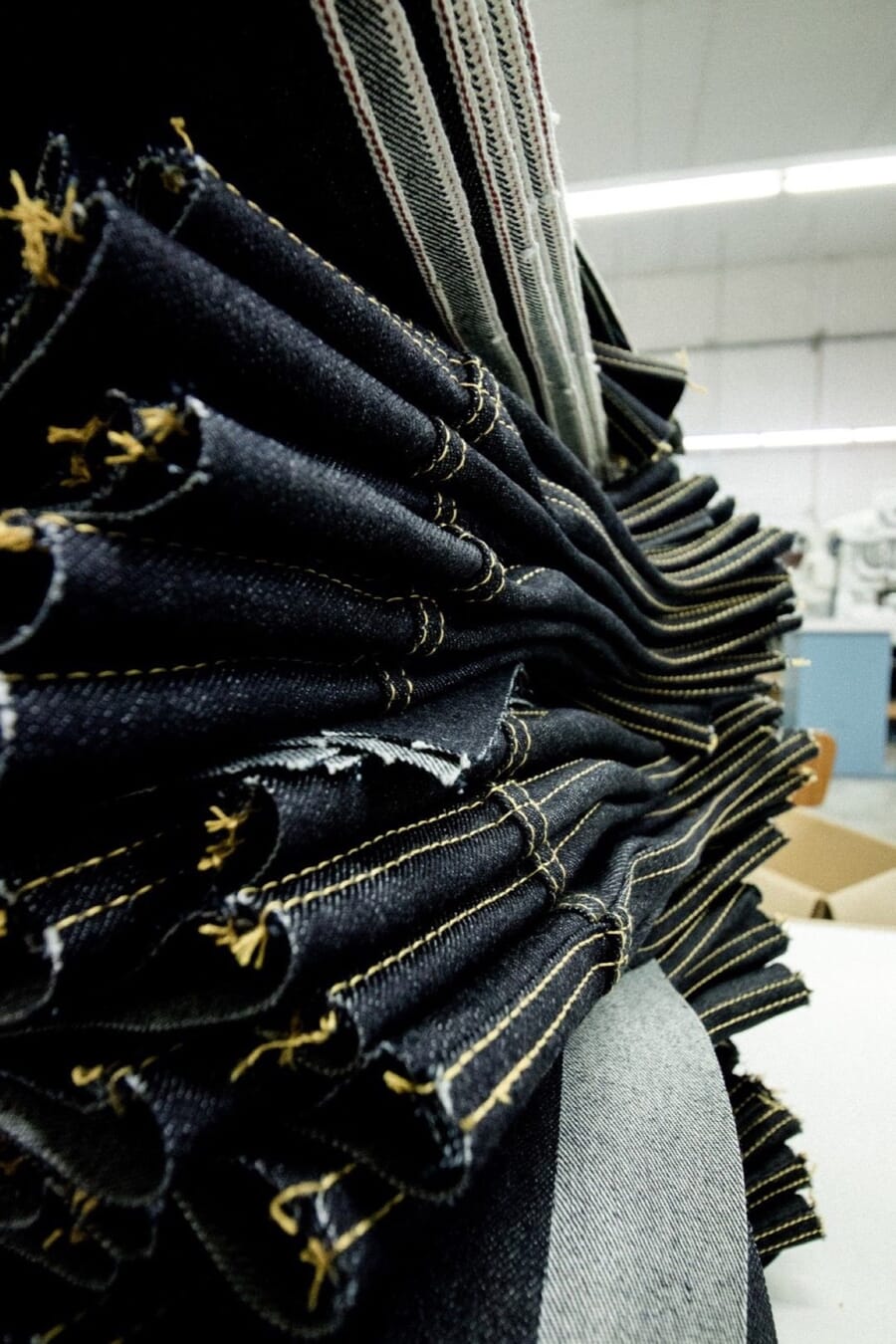 Stack of dark denim with chain-stitched hems in a factory