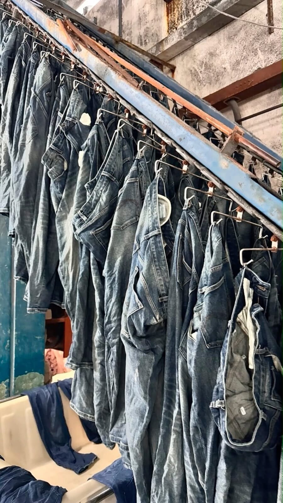 Washed jeans hanging on a rail in a denim finishing room