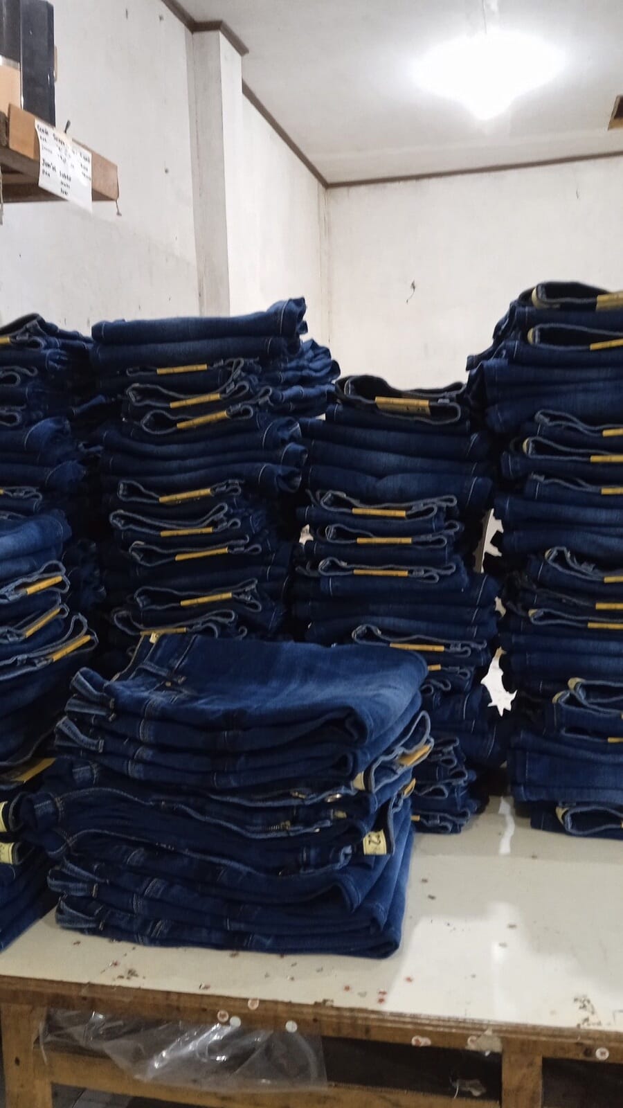 Stacks of finished dark jeans on a packing table