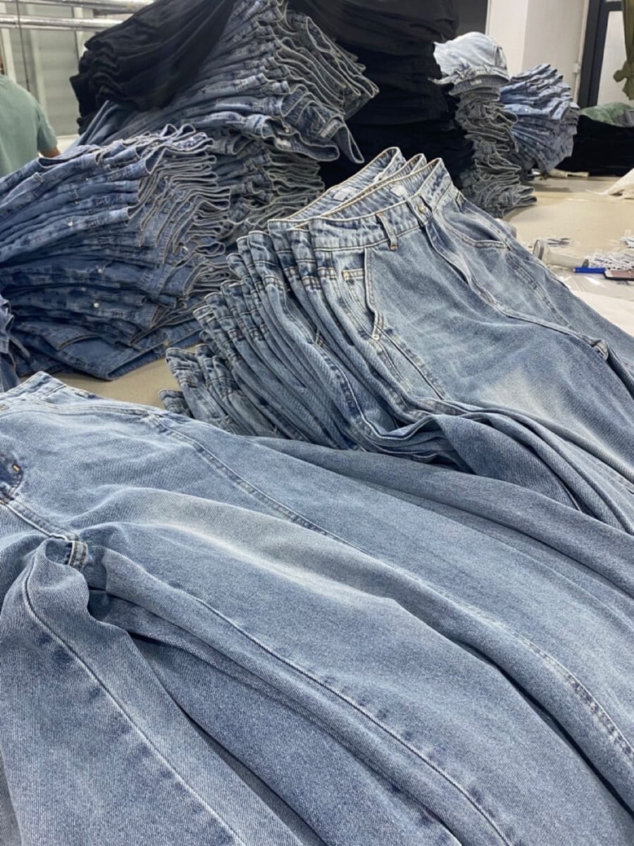 Pile of light-wash jeans on a work table