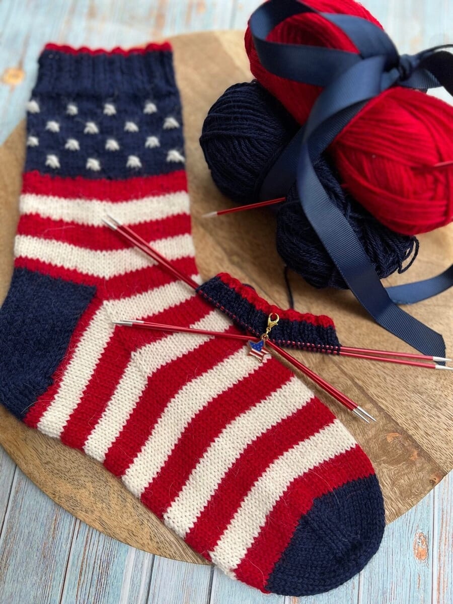 Knitted socks in red, white and blue stripes and stars with yarn balls