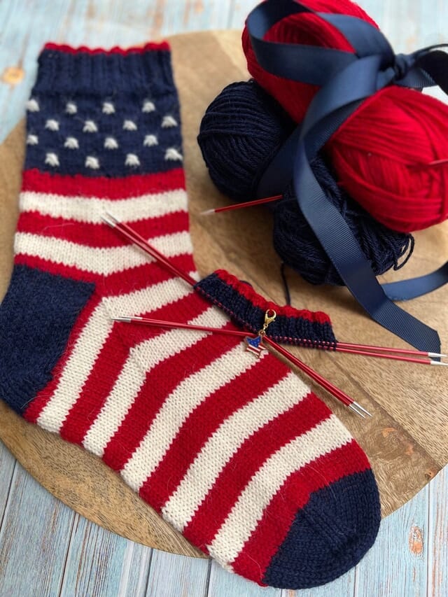 Knitted socks in red, white and blue stripes and stars with yarn balls
