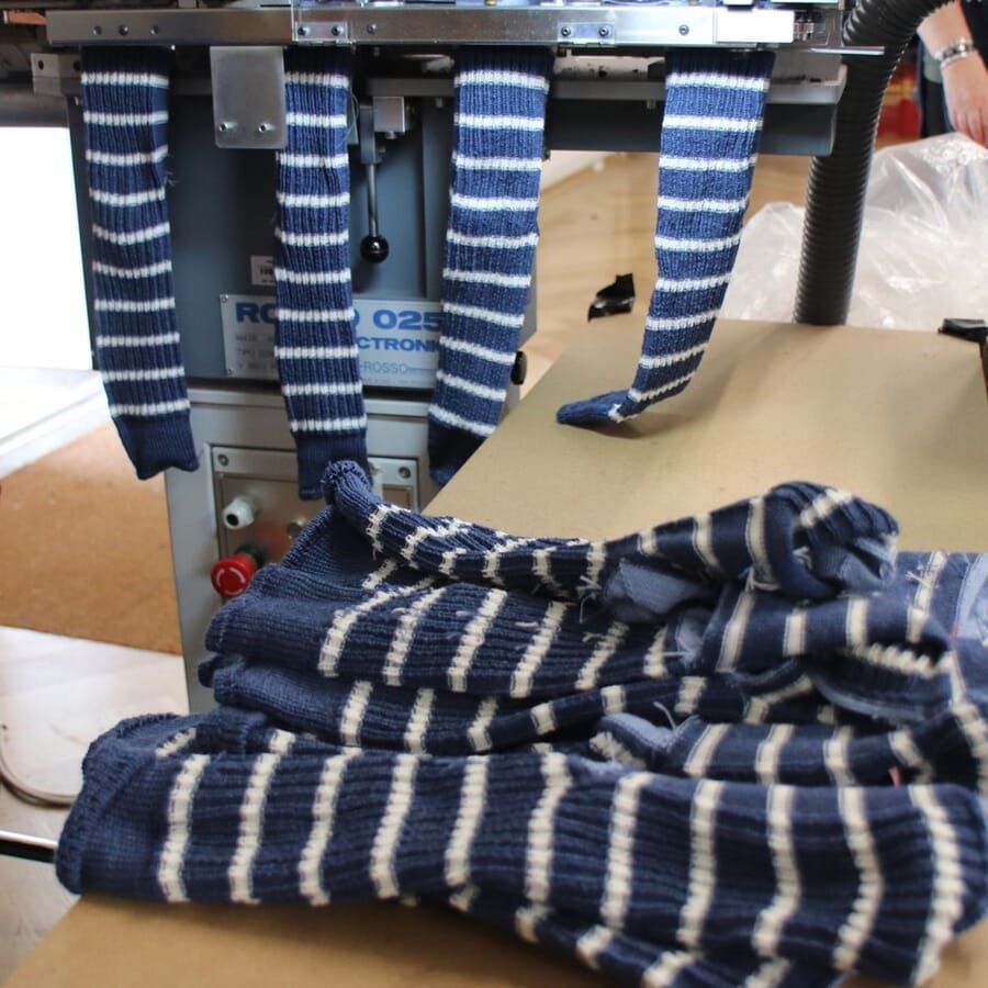 Striped navy and white knit tubes coming off a knitting machine