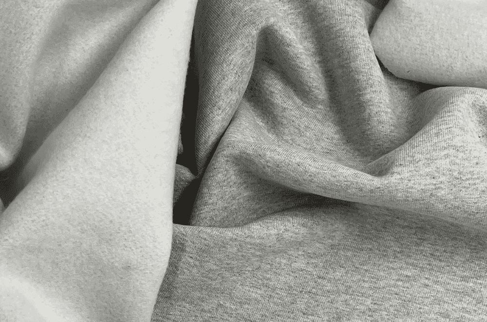 Close-up of soft brushed fleece fabric texture in neutral tones, showing the raised nap that gives polar fleece its warmth.