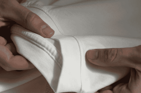 Hands checking the ribbed hem of a sweatshirt