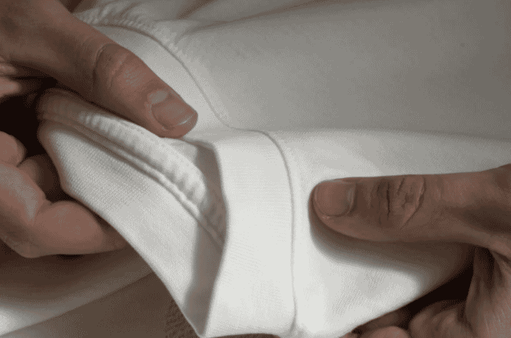Hands checking the ribbed hem of a sweatshirt