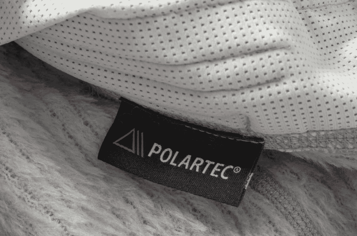 A Polartec brand label stitched into the seam of a fleece garment, with mesh lining above and brushed pile below.
