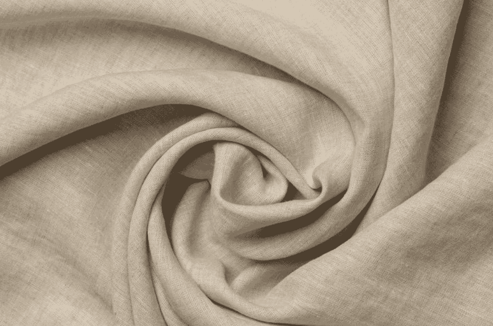 Rolls of natural undyed linen fabric stacked at a Portuguese textile mill, showing the characteristic slubby weave and neutral flax colour.