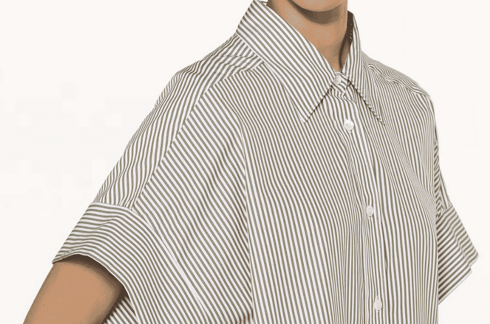 Close-up detail of a white cotton poplin shirt showing the fine flat surface and subtle horizontal weave rib characteristic of premium shirting fabric.