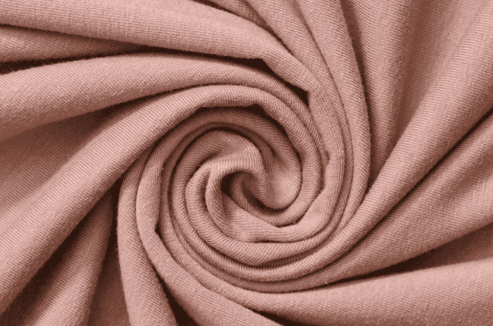 Close-up detail of soft cotton single jersey knit fabric showing the tight vertical wales and smooth surface typical of a t-shirt weight knit.