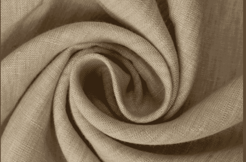Rolls of soft, drapey bamboo viscose fabric in natural tones stacked at a Portuguese textile mill, showing the silky surface typical of regenerated cellulosic fibres.
